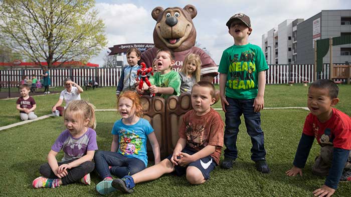 Children posing with the Boomer Bear statue at the MSU Child Development Center. 