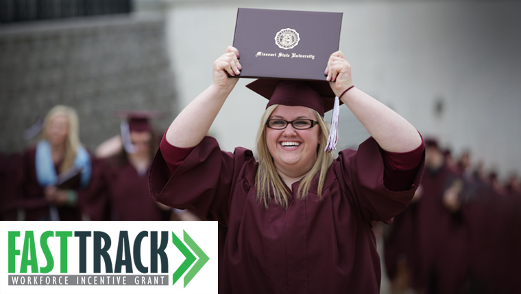 A Missouri State graduate walking with her cap and gowns and holding her diplomas