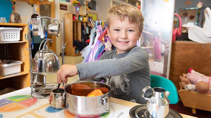 Young child pretending to cook at a play kitchen. 