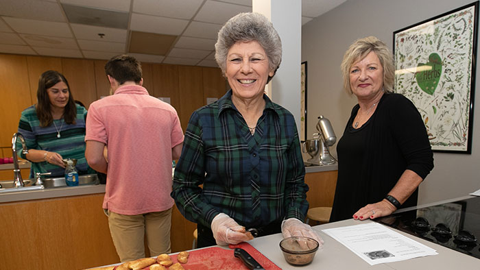 Older woman with gray hair preparing a recipe in a nutrition class. 